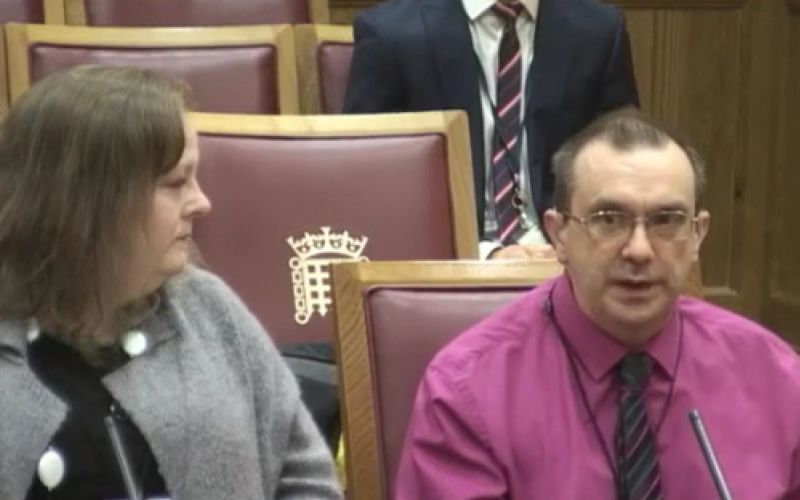 Andrew Brenton giving evidence to the committee, watched by his wife