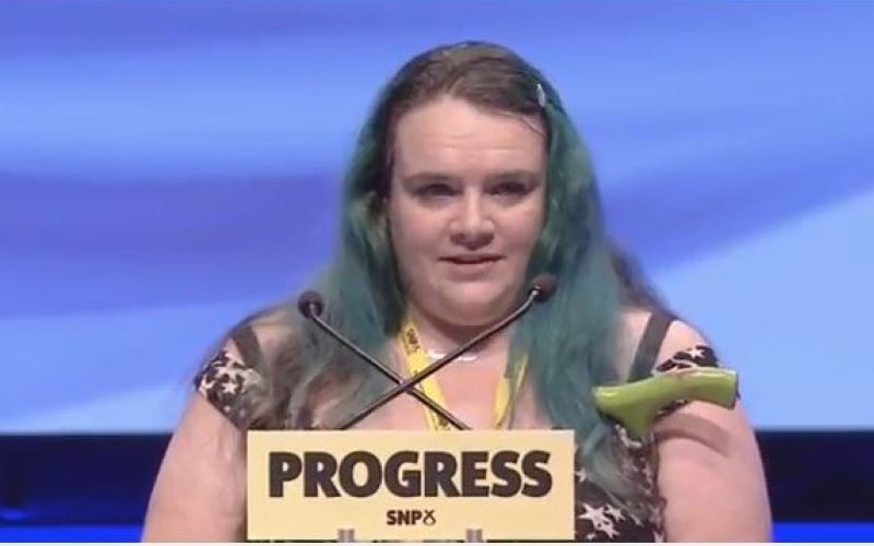 Fiona Robertson speaking to the SNP conference above a sign saying 'Progress'