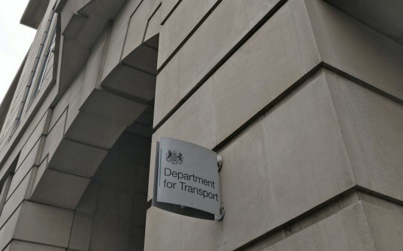 A wall with a grey Department for Transport sign sticking out of it
