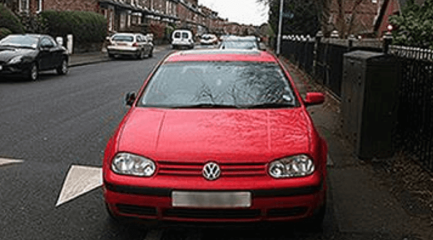A red car parked on a pavement