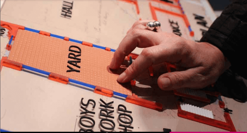 A hand touches a tactile map of a museum