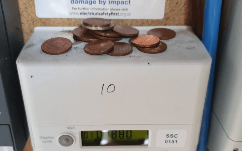 A pile of coins on a dusty electricity meter