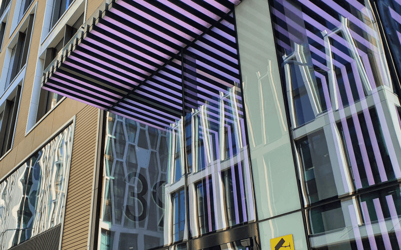 The glass frontage of an office building, with purple and black strips
