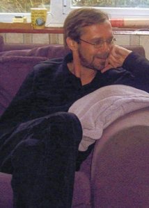 Stephen Carré smiling, on a purple sofa